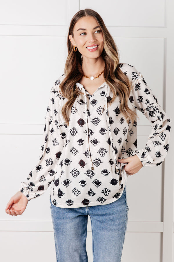Woman wearing a floral blouse and jeans against a white background
