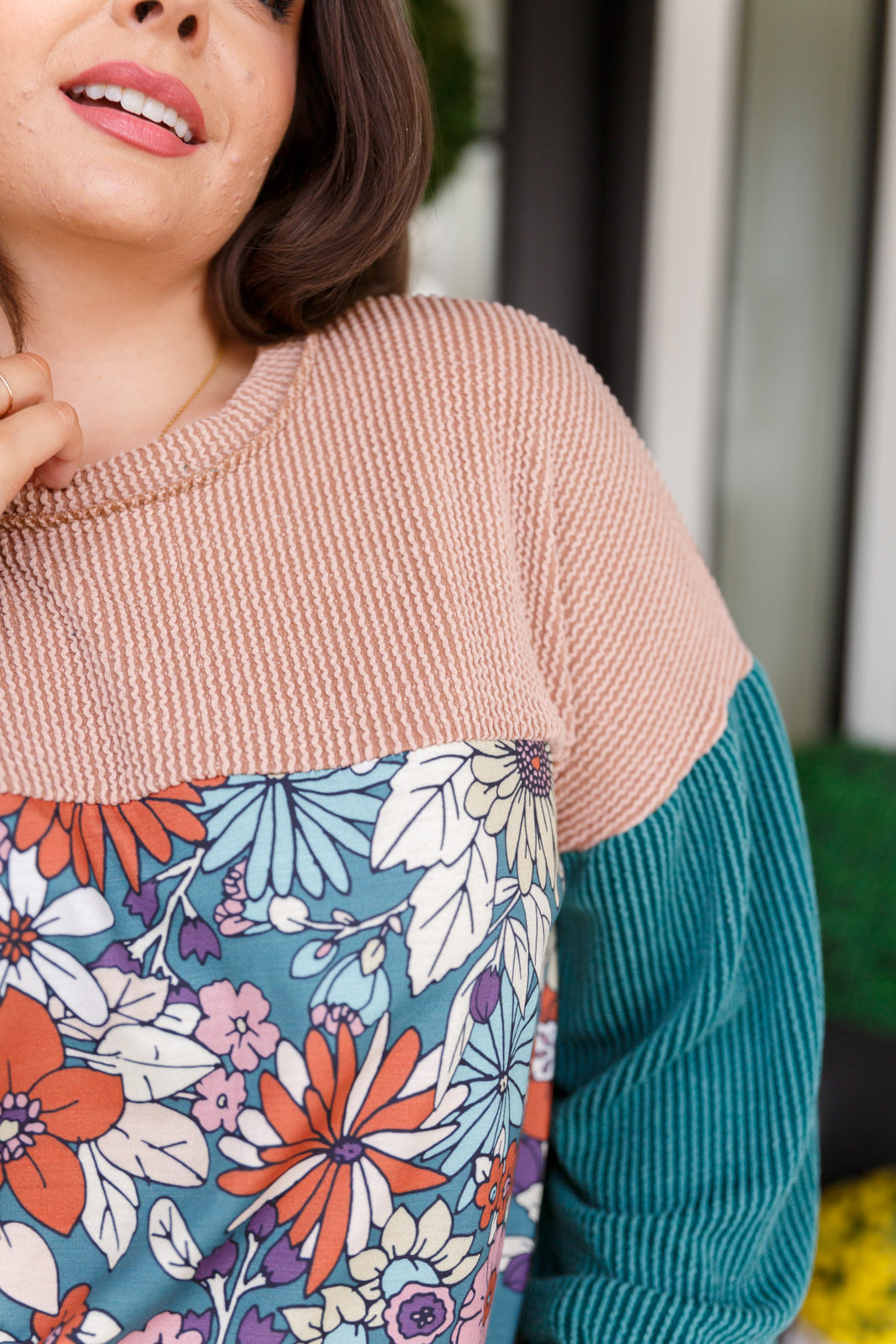 Person wearing a sweater with a floral pattern on a blurred background