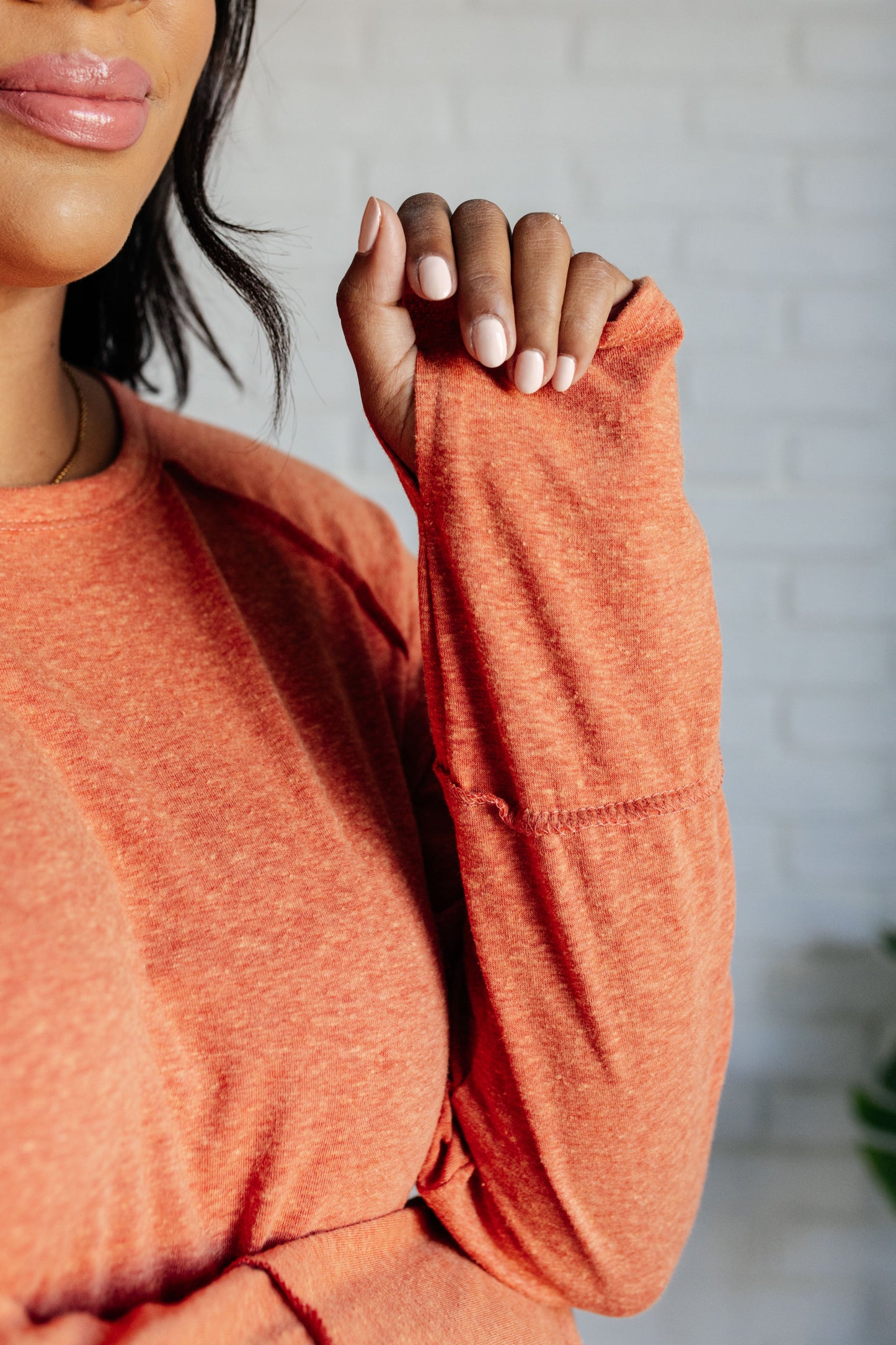 Person wearing an orange long-sleeve top with a blurred background