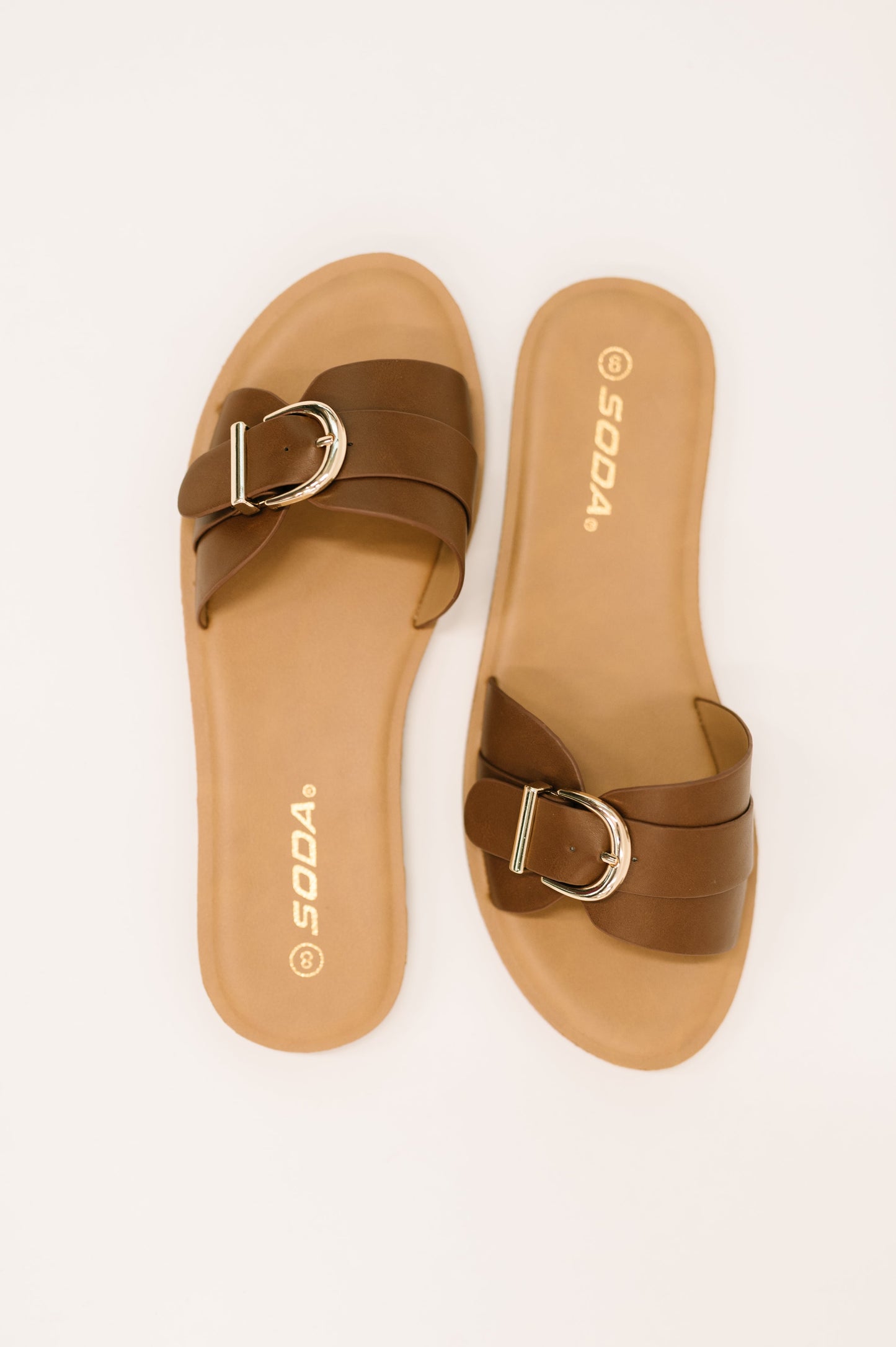 Brown sandals with a gold buckle on a white background
