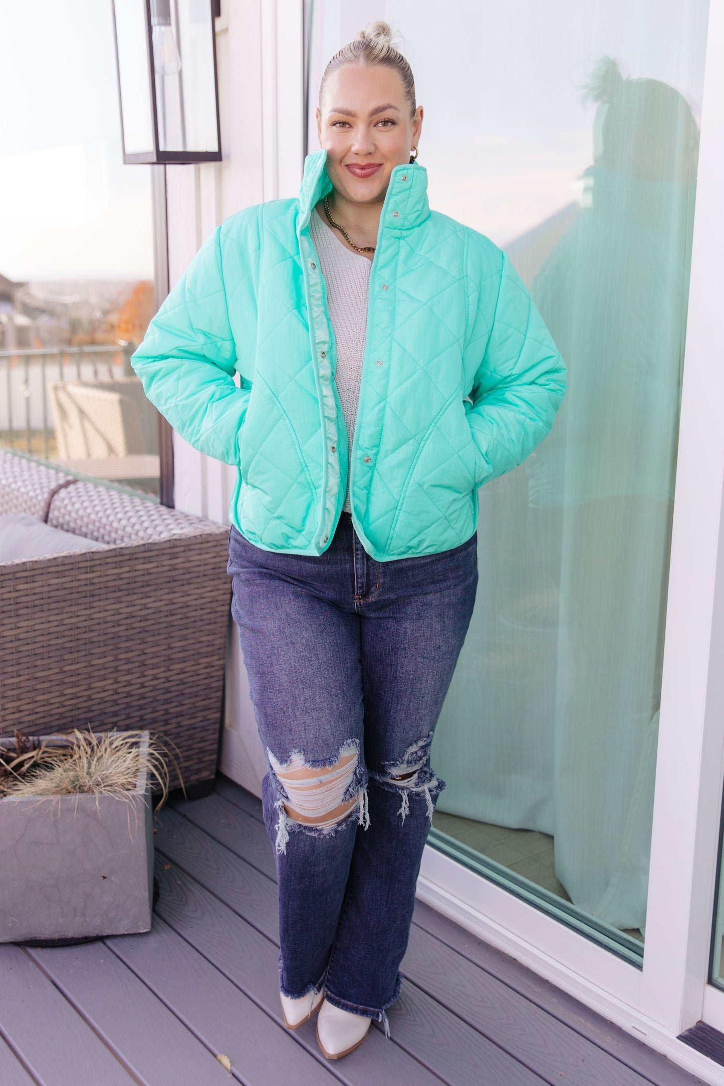 Person wearing a light blue puffer jacket on a balcony