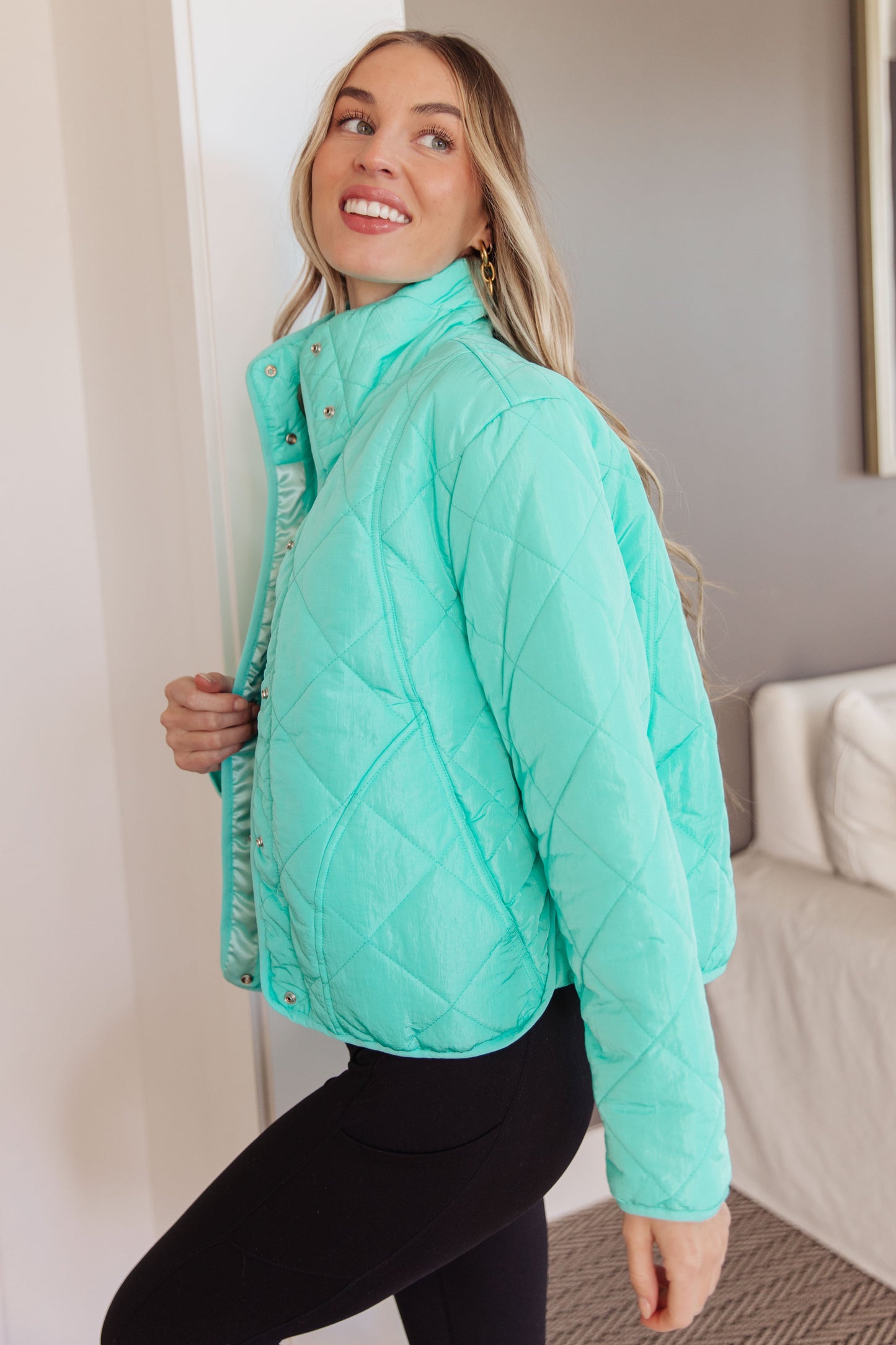 Woman wearing a teal quilted jacket in an indoor setting