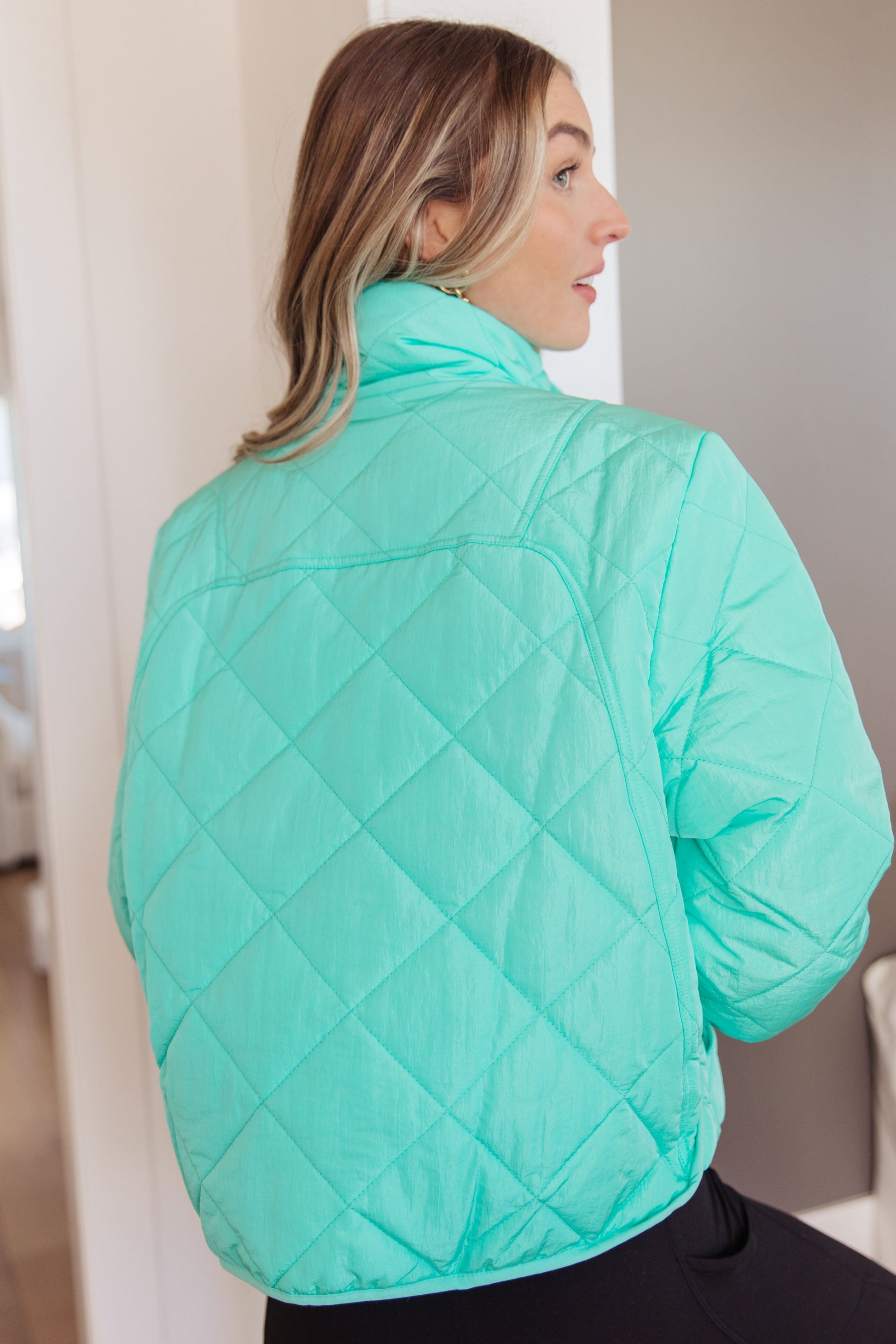 Woman wearing a light blue quilted jacket indoors