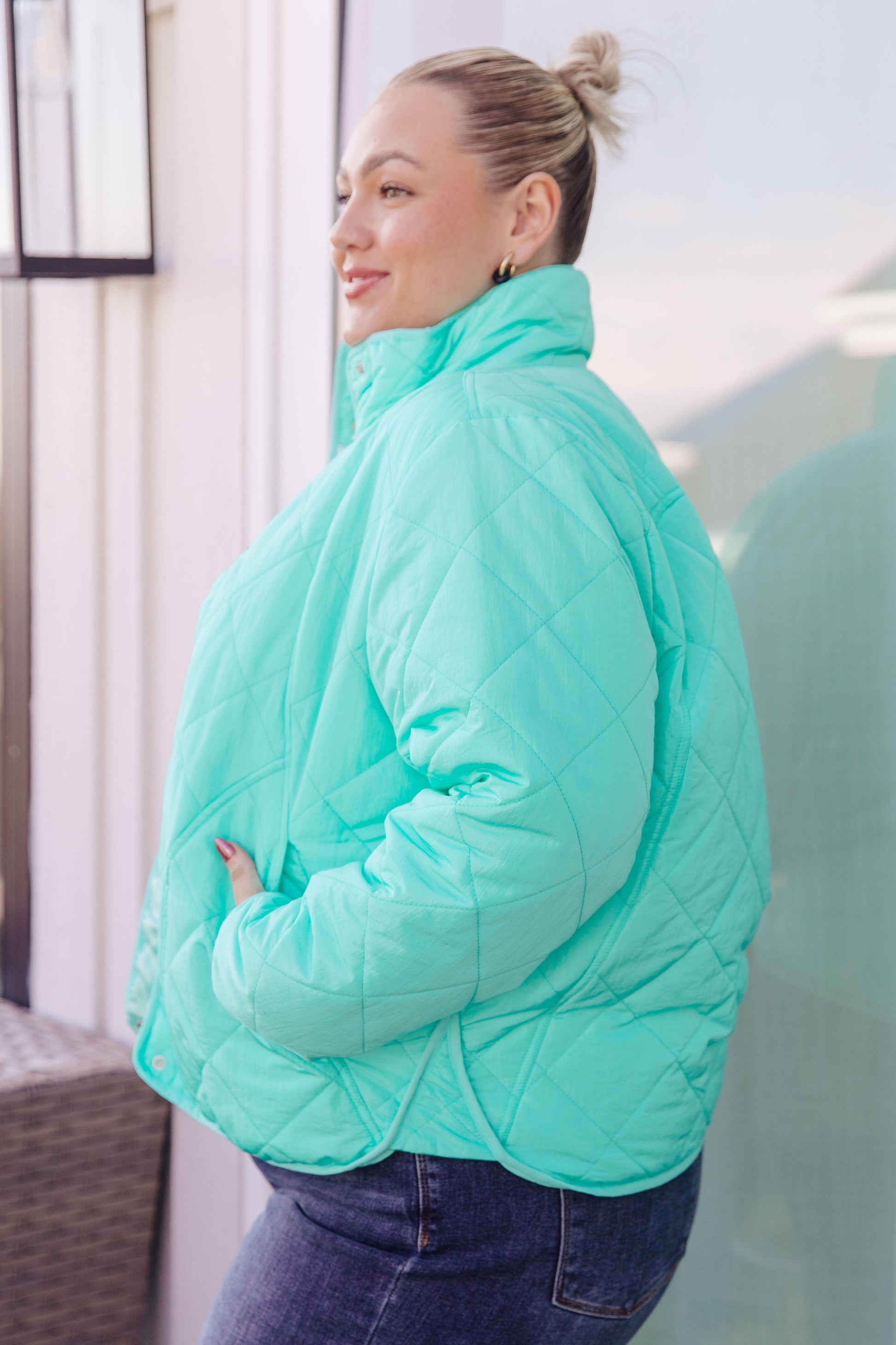 Person wearing a light blue quilted jacket standing indoors.