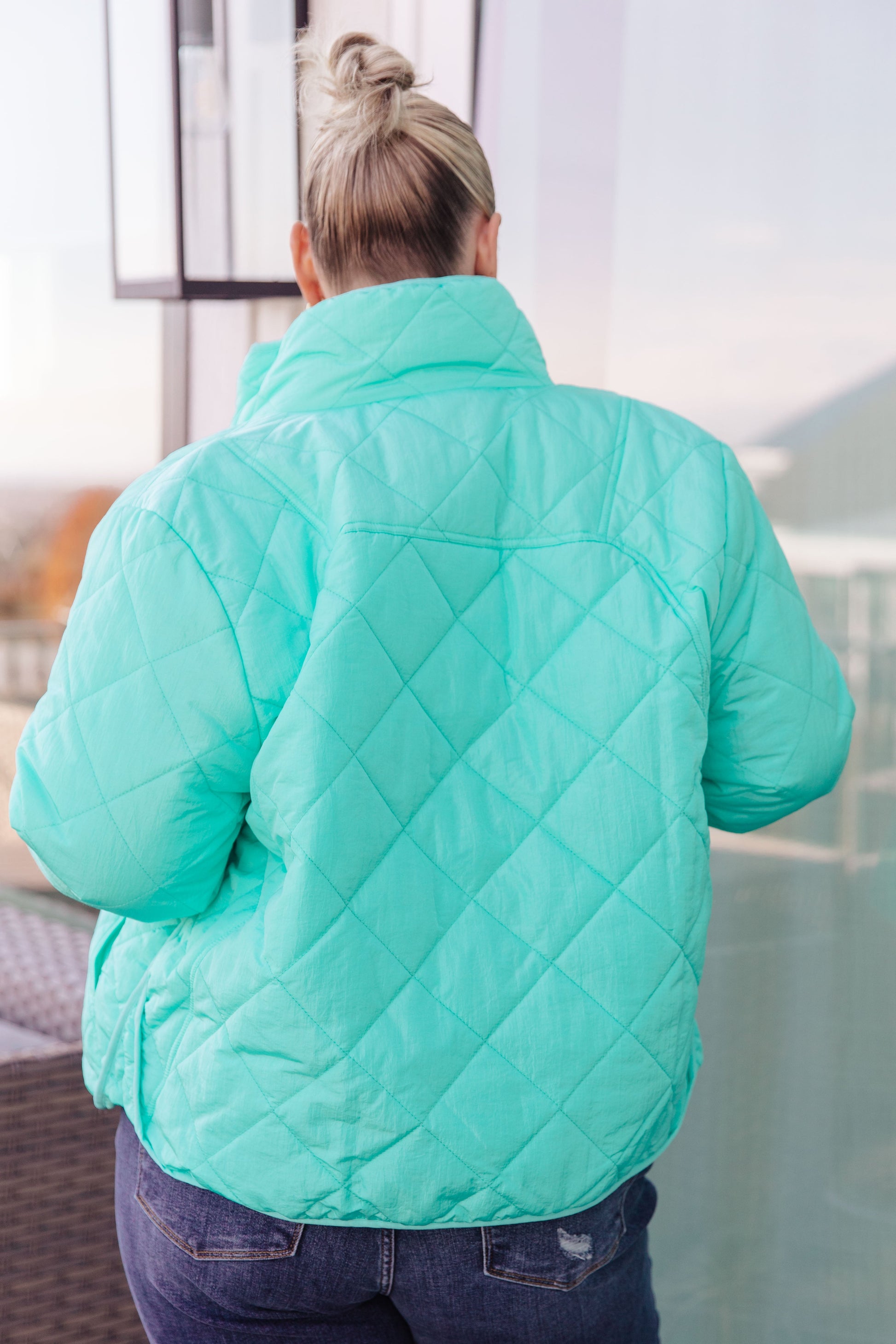 Person wearing a teal quilted jacket in an indoor setting