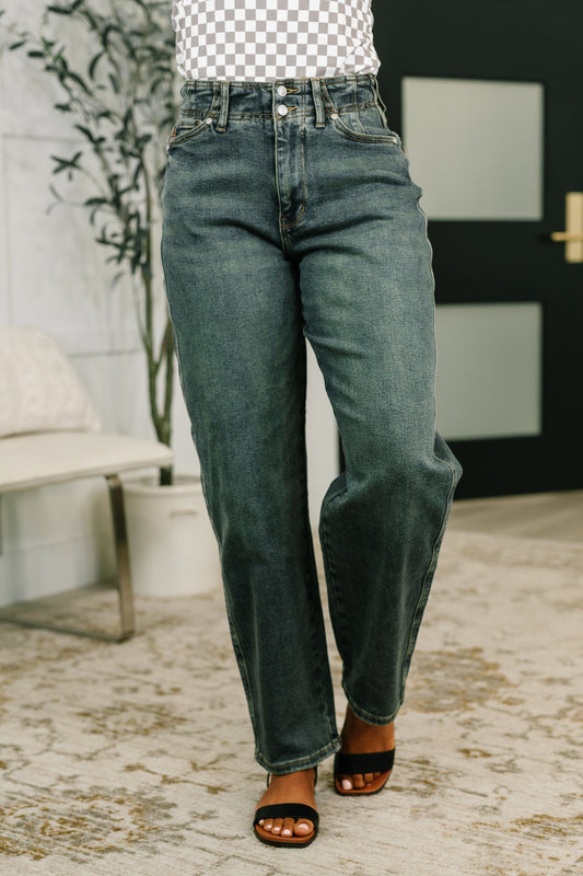 Person wearing blue jeans standing indoors with a blurred background