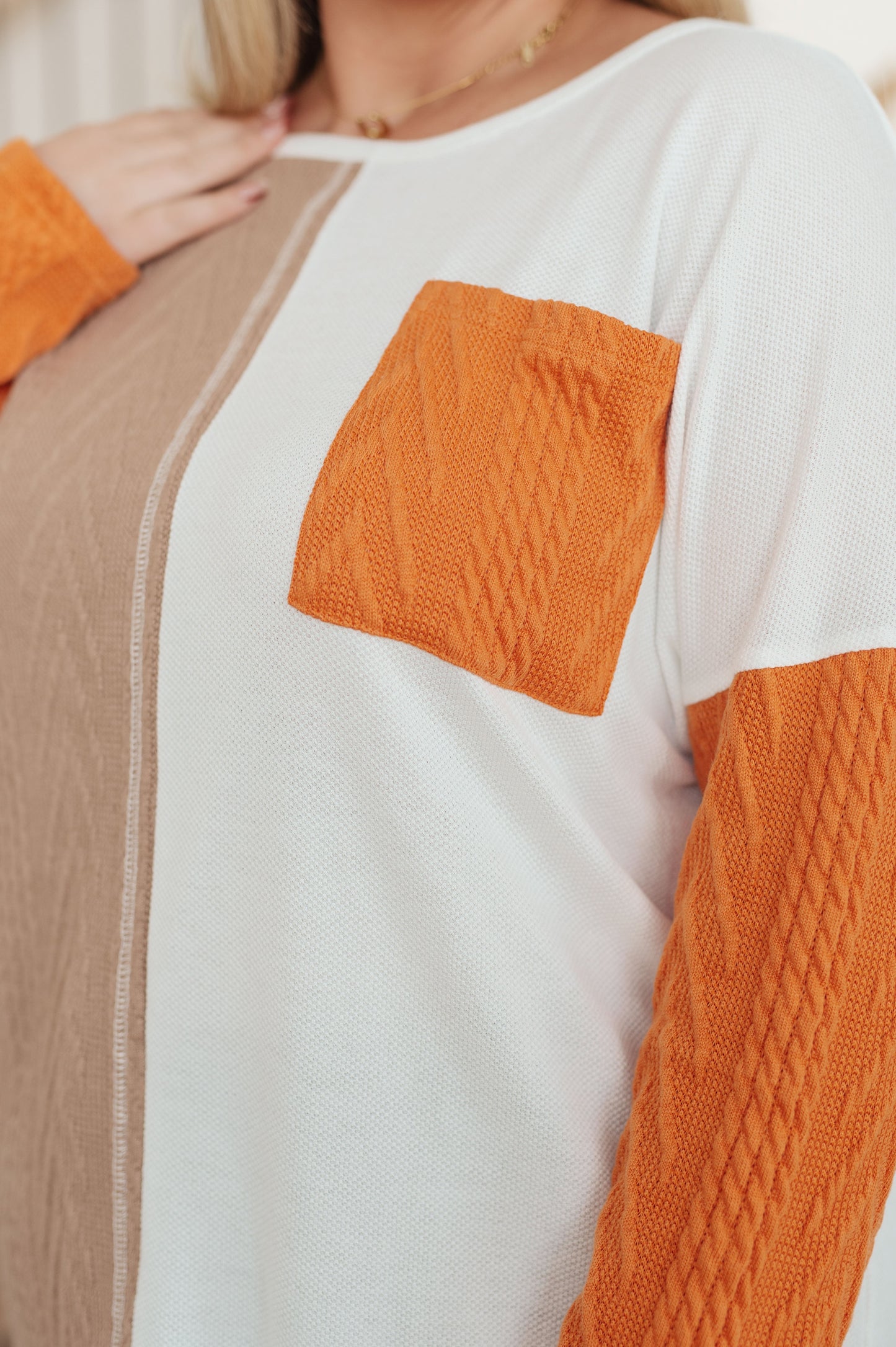 Close-up of a sweater with orange and beige patterned sections.