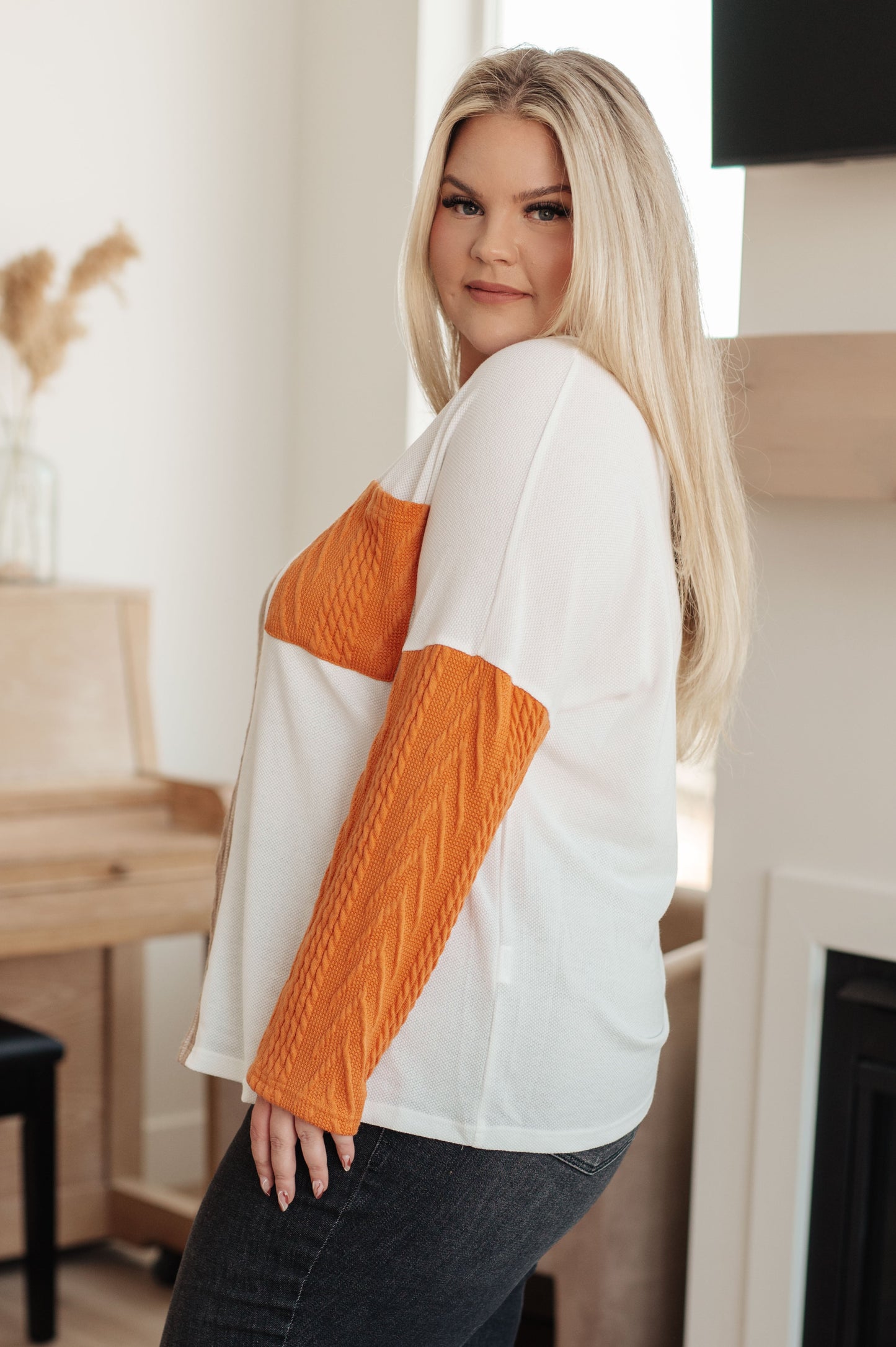 Woman wearing a white and orange sweater in an indoor setting
