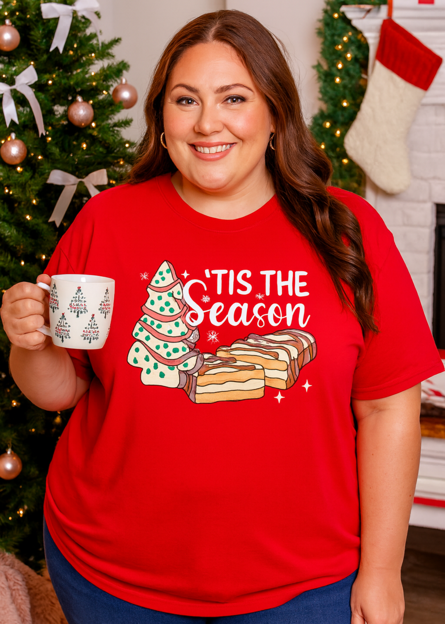Person wearing a red Christmas-themed t-shirt with a mug in a festive setting.
