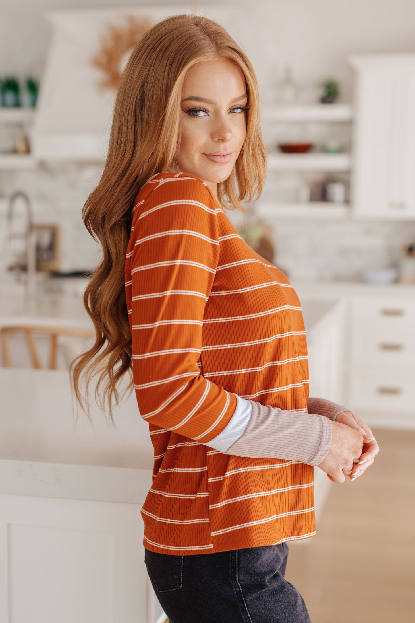 Woman wearing an orange striped shirt in a kitchen setting