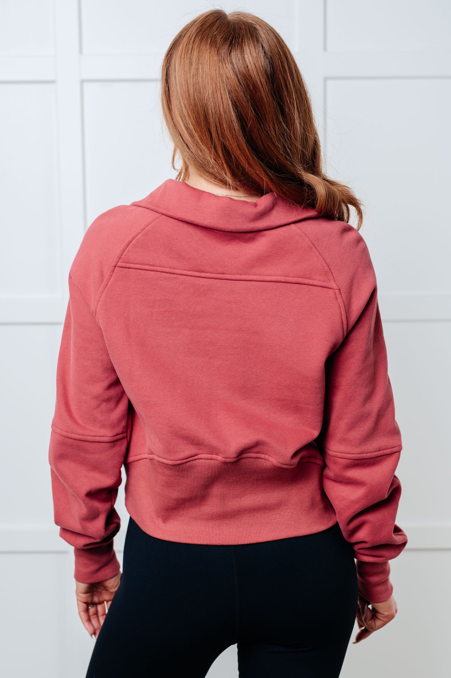 Person wearing a pink jacket against a white tiled wall