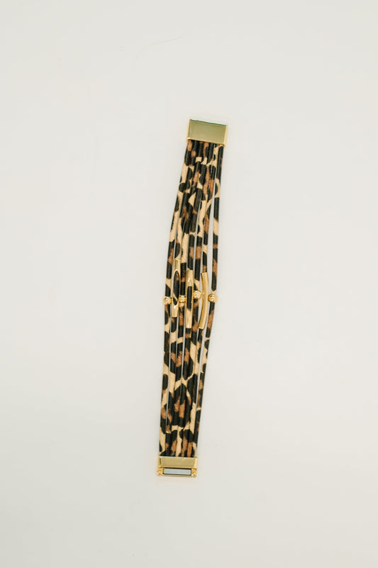 Leopard print belt with gold buckle on a light gray background