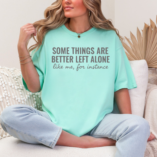 Person wearing a light blue t-shirt with text, sitting on a couch.
