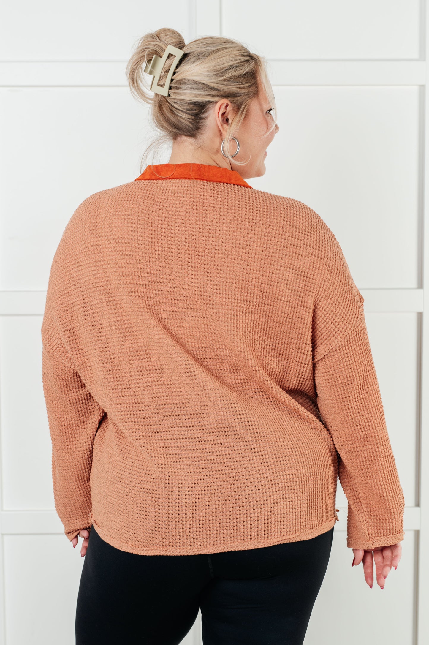 Woman wearing a brown textured sweater against a white background