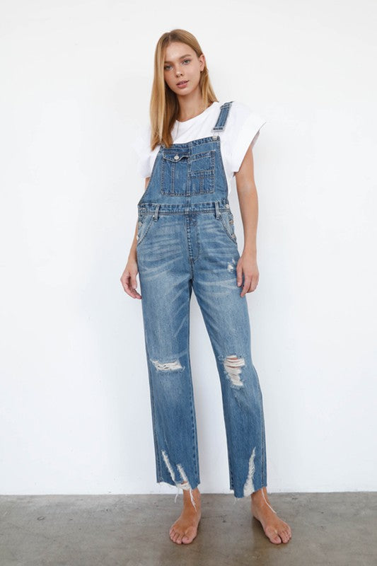 Person wearing blue denim overalls with a white background