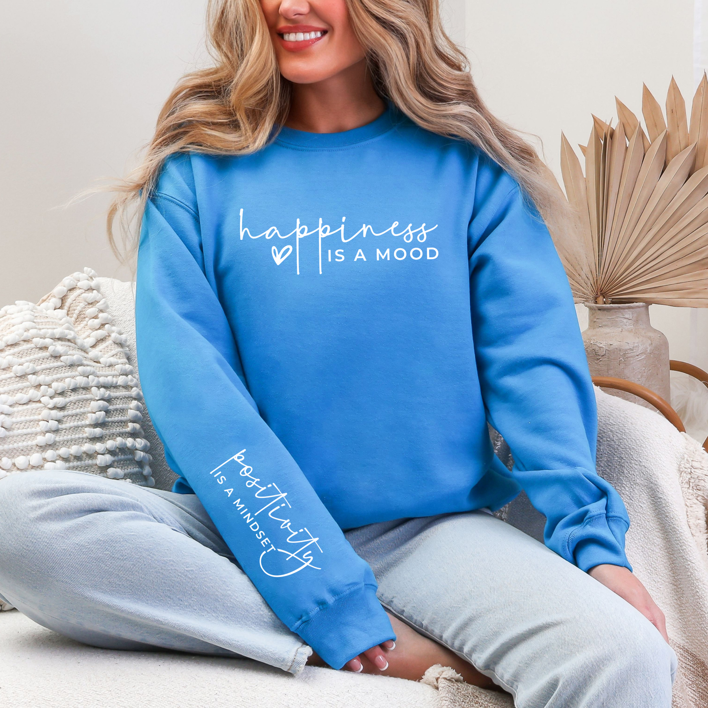 Person wearing a blue sweatshirt with text, sitting on a couch.