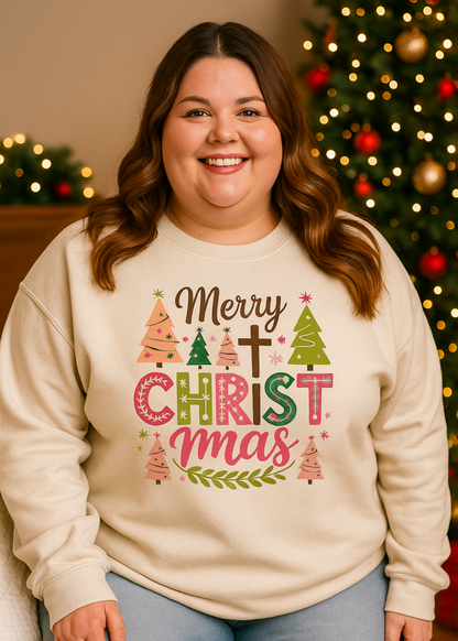 Person wearing a Christmas-themed sweatshirt with decorative text and graphics, standing in front of a decorated Christmas tree.