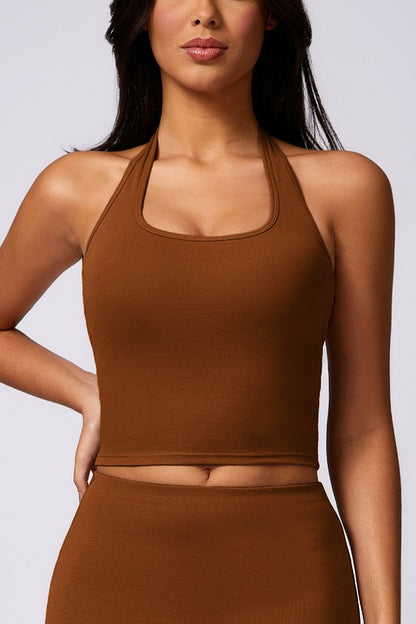 Woman wearing a brown halter top and skirt set against a plain background