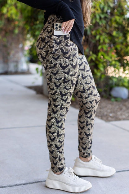 Person wearing patterned pants and white sneakers on a sidewalk.