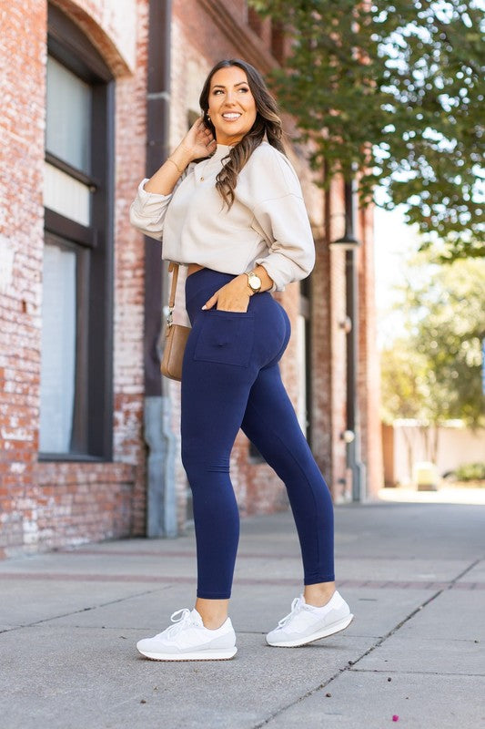 Woman wearing navy leggings and a light-colored top on a city street.