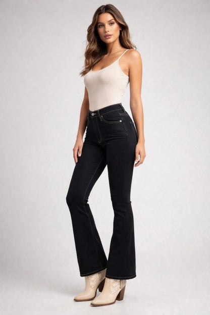 Woman wearing black flared jeans and a white top on a gray background