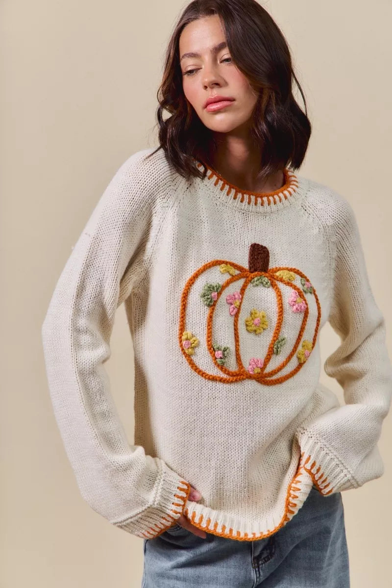 Woman wearing a sweater with a pumpkin design on a beige background