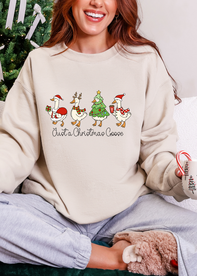Person wearing a cream sweatshirt with Christmas-themed design, sitting in front of a decorated Christmas tree.
