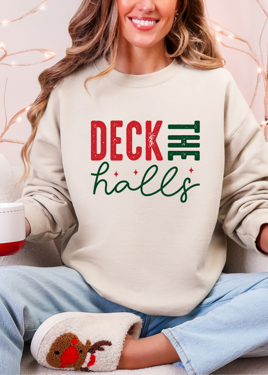 Person wearing a 'Deck the Halls' sweater holding a mug with a gingerbread man design, sitting on a couch.