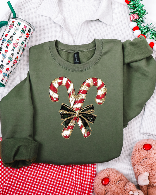 Green sweatshirt with candy cane design on a festive background with tinsel and mug.