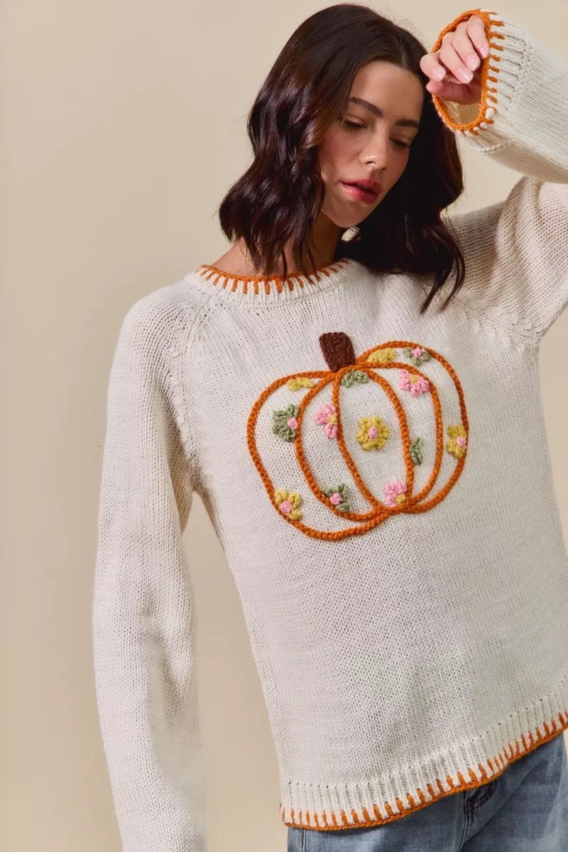 Woman wearing a sweater with a pumpkin design on a beige background