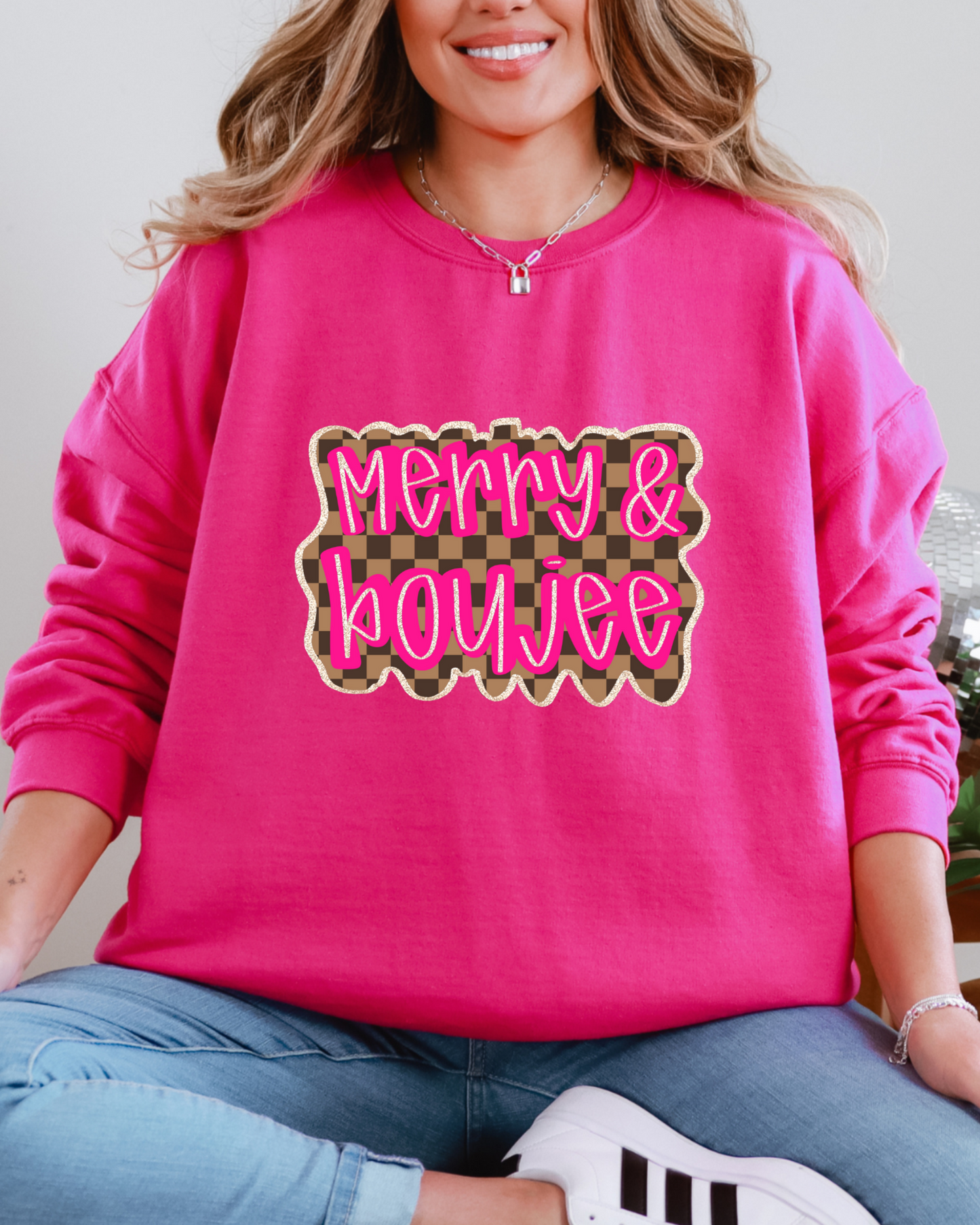 Person wearing a pink sweatshirt with 'Merry & Boujee' text