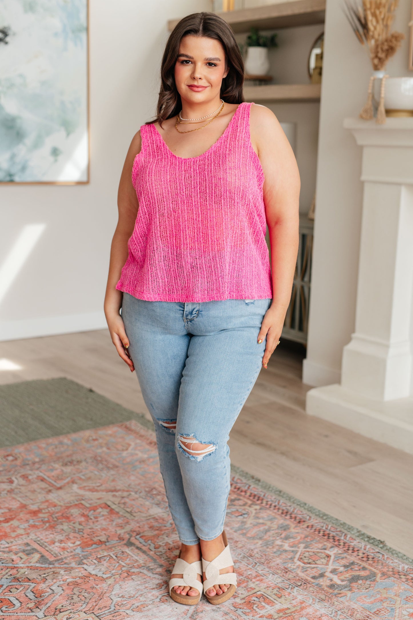 A woman wearing a pink knit V-neck tank top with an A-line silhouette.