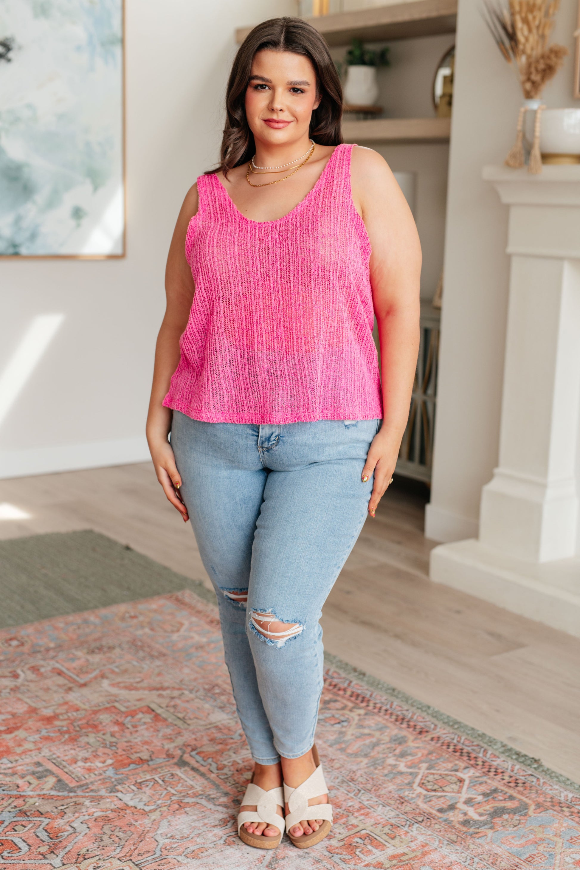 A woman wearing a pink knit V-neck tank top with an A-line silhouette.