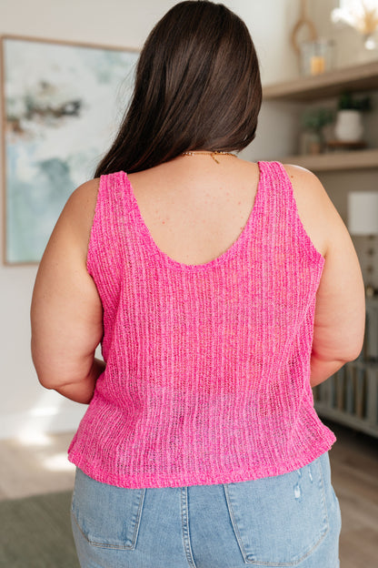 A woman wearing a pink knit V-neck tank top with an A-line silhouette.