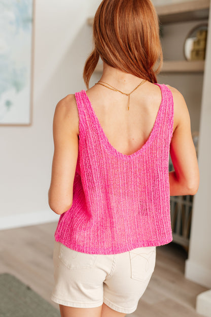 A woman wearing a pink knit V-neck tank top with an A-line silhouette.