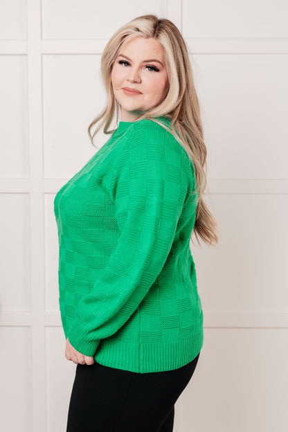 Woman wearing a green sweater against a white tiled wall
