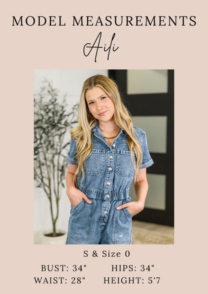 Woman wearing a denim jumpsuit with model measurements displayed.