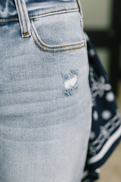 Close-up of light blue denim jeans with a distressed pocket detail.