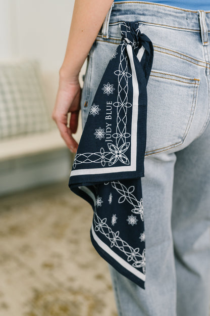 Person wearing a navy bandana with white patterns and text on light blue jeans.