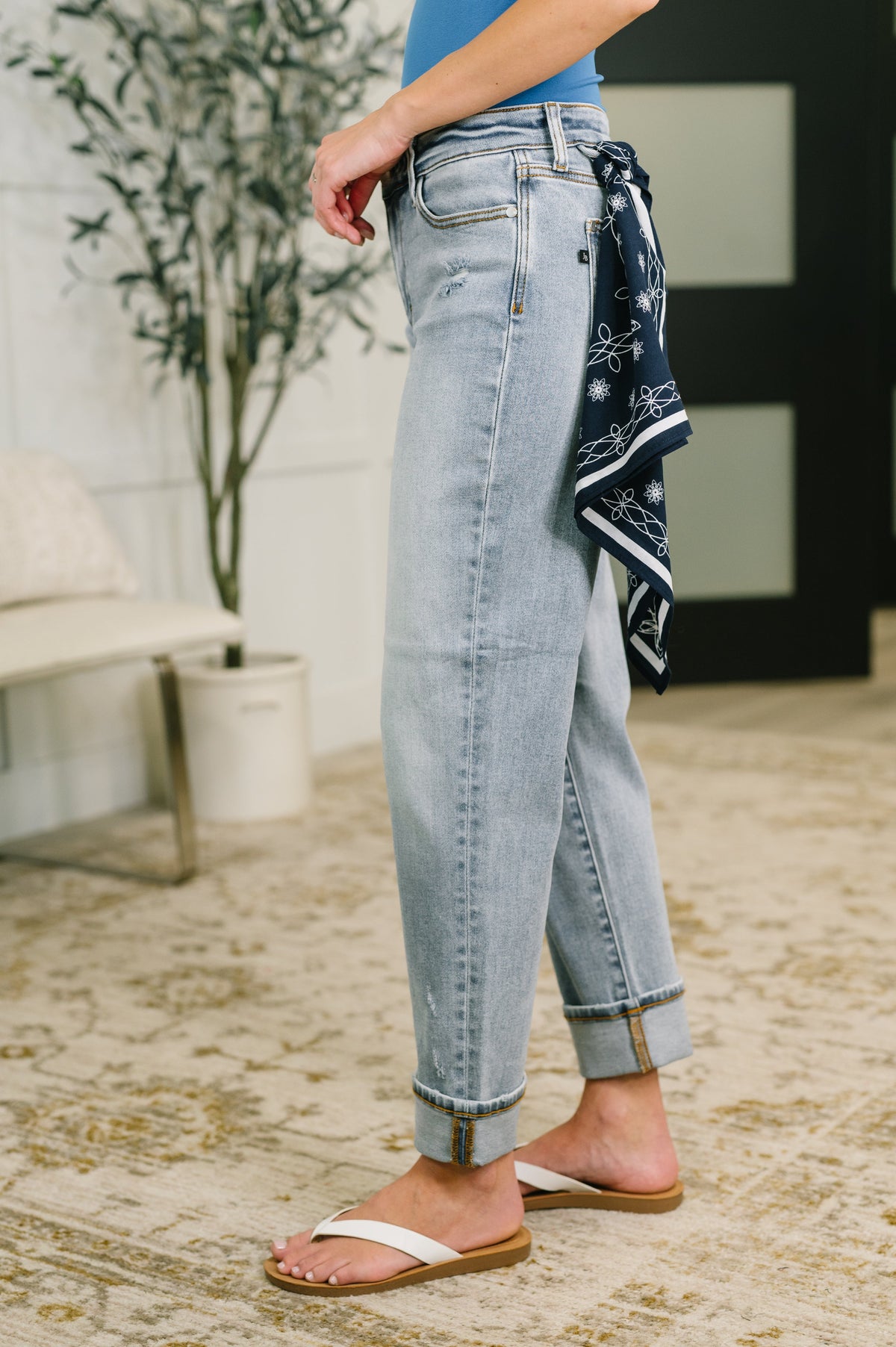 Person wearing light blue jeans with a bandana, standing indoors.