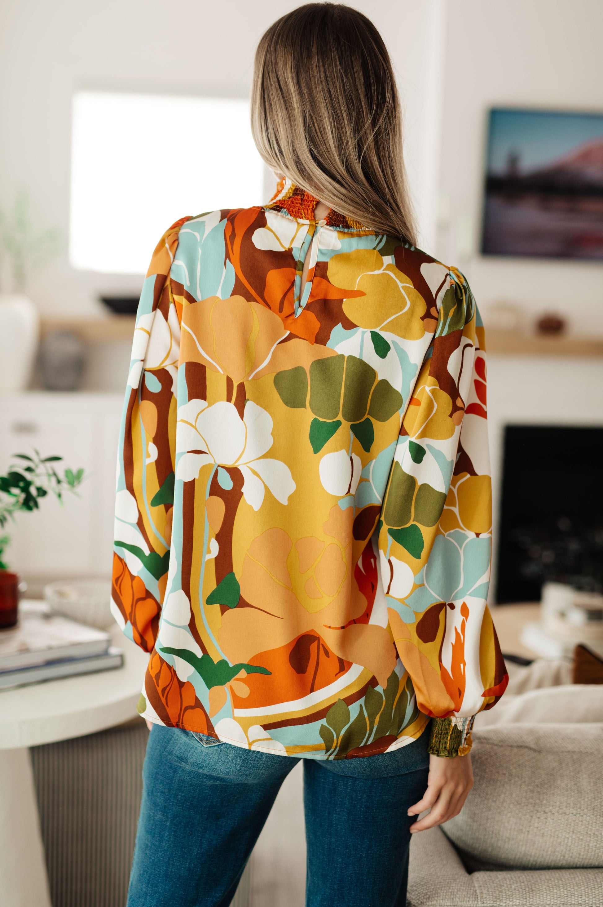 Person wearing a colorful floral blouse in a living room setting