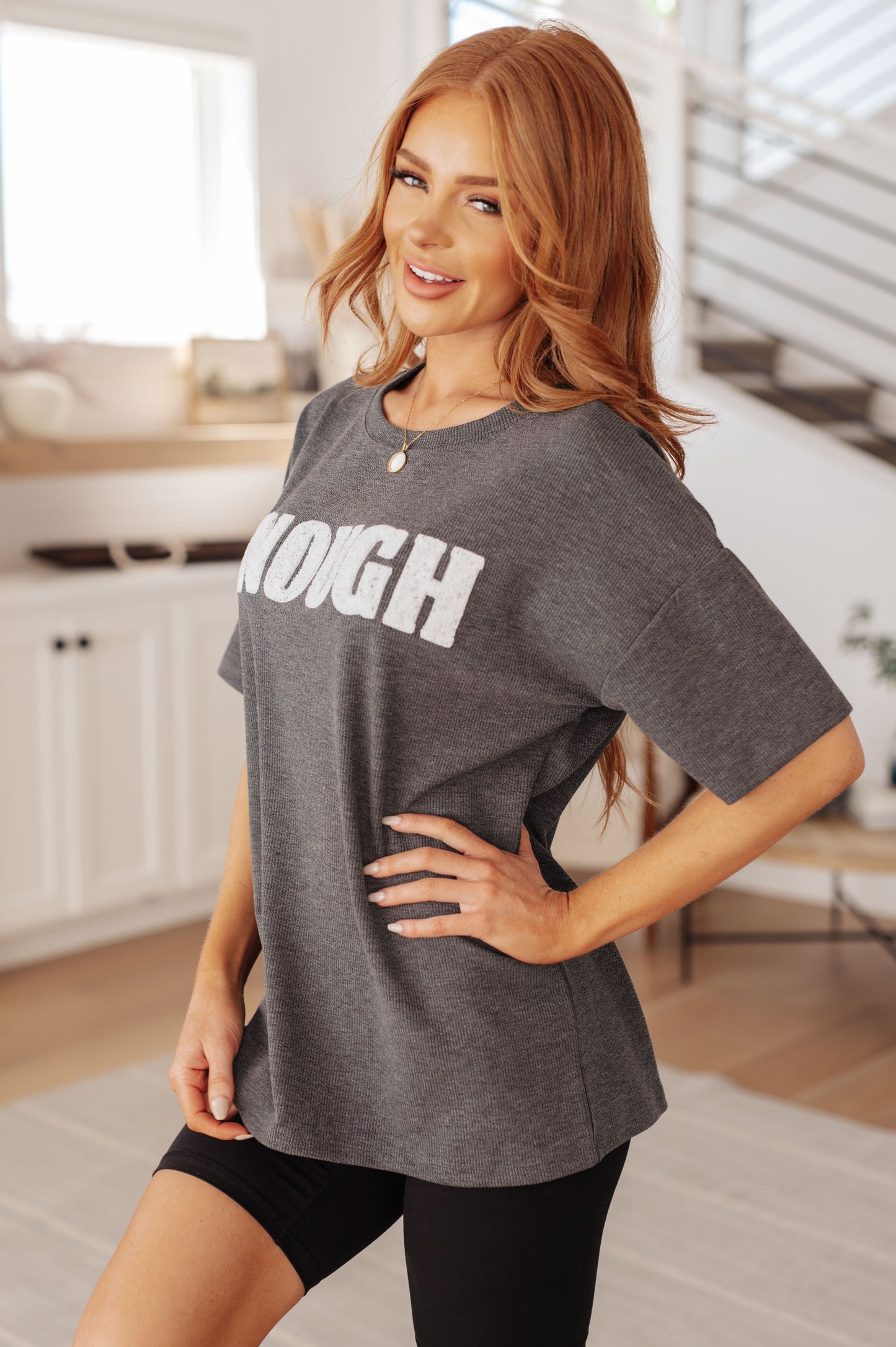 Woman wearing a gray t-shirt with 'STRONG' printed on it in a kitchen.