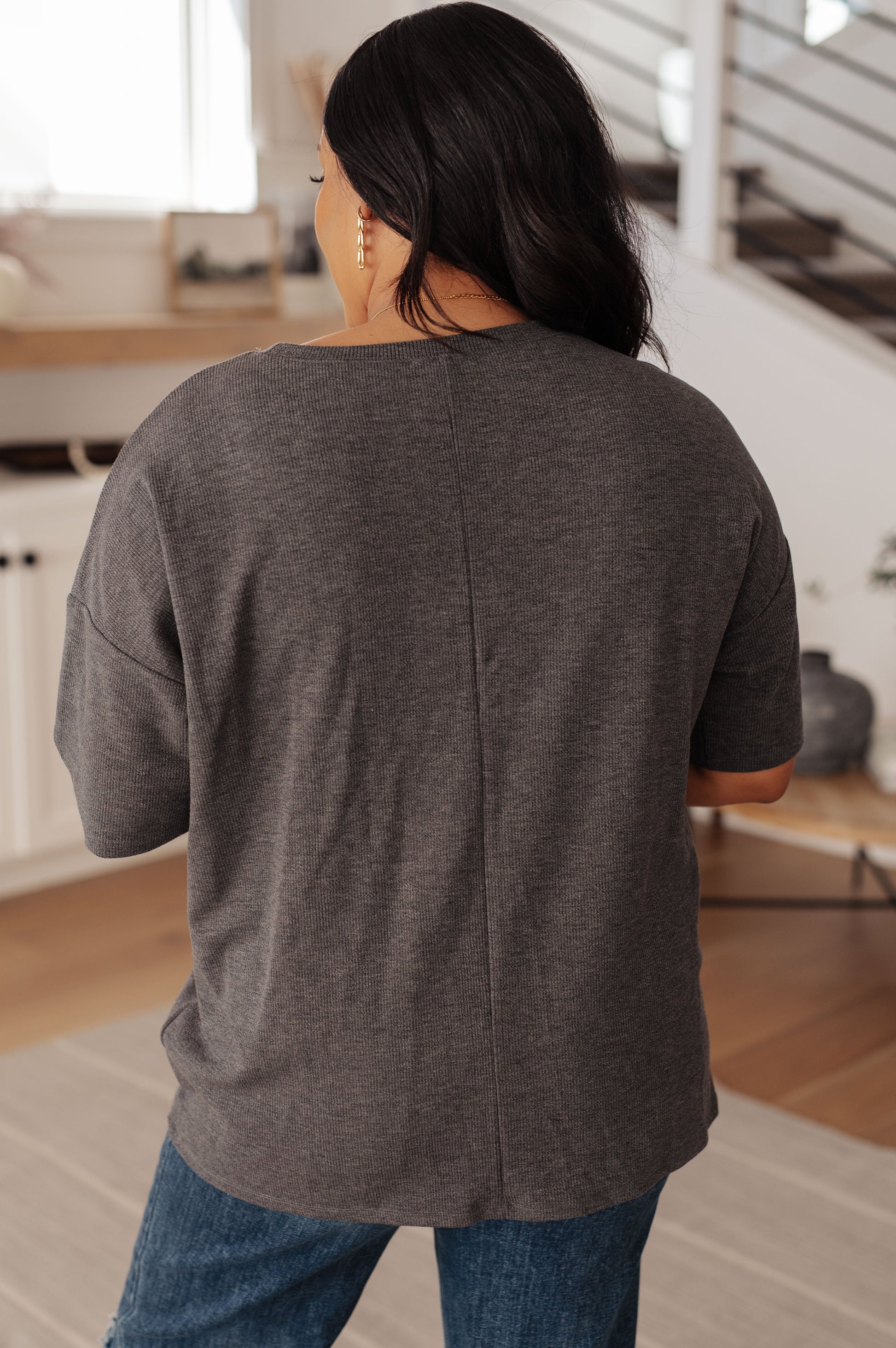 Person wearing a gray oversized shirt in a kitchen setting