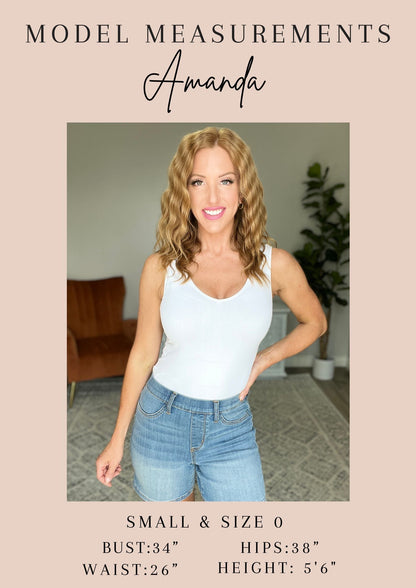 Woman wearing a white tank top and blue jeans with model measurements displayed.