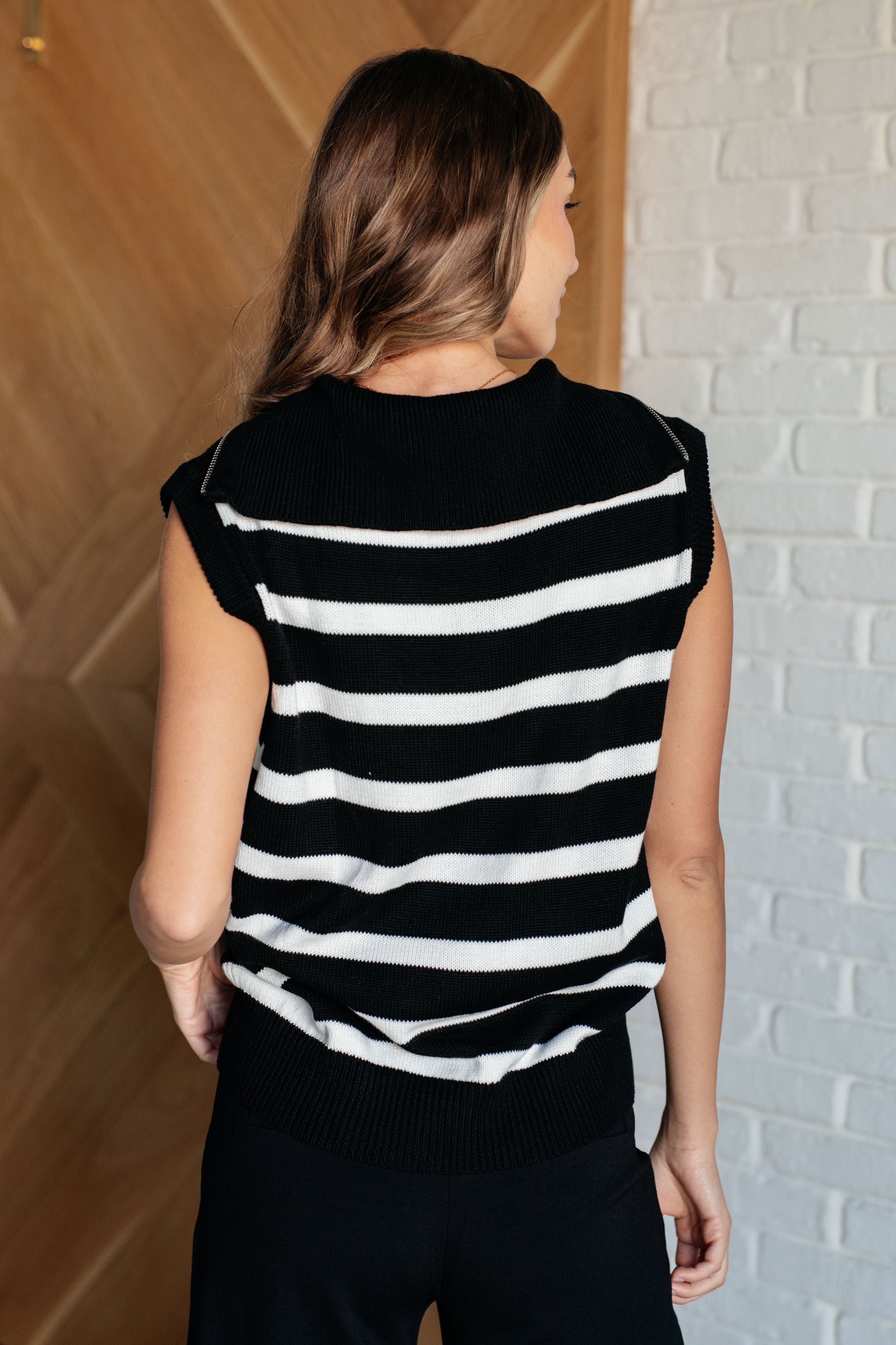 Person wearing a black and white striped shirt against a brick wall.