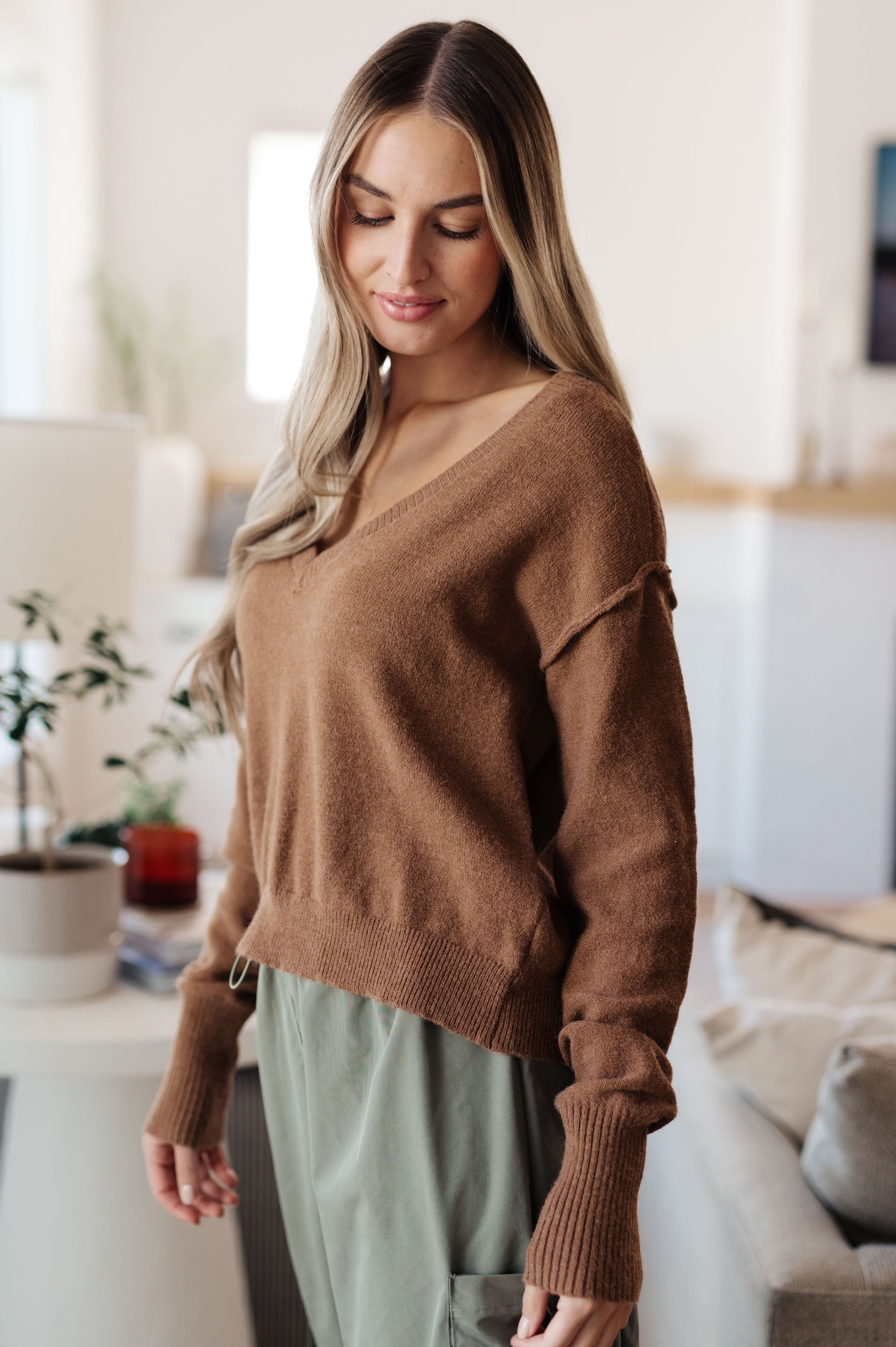Woman wearing a brown sweater in a living room setting