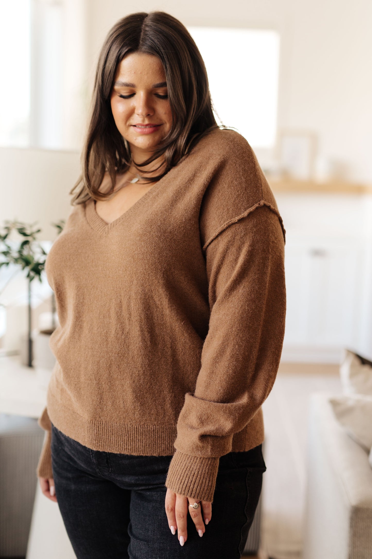 Woman wearing a brown sweater in a bright room