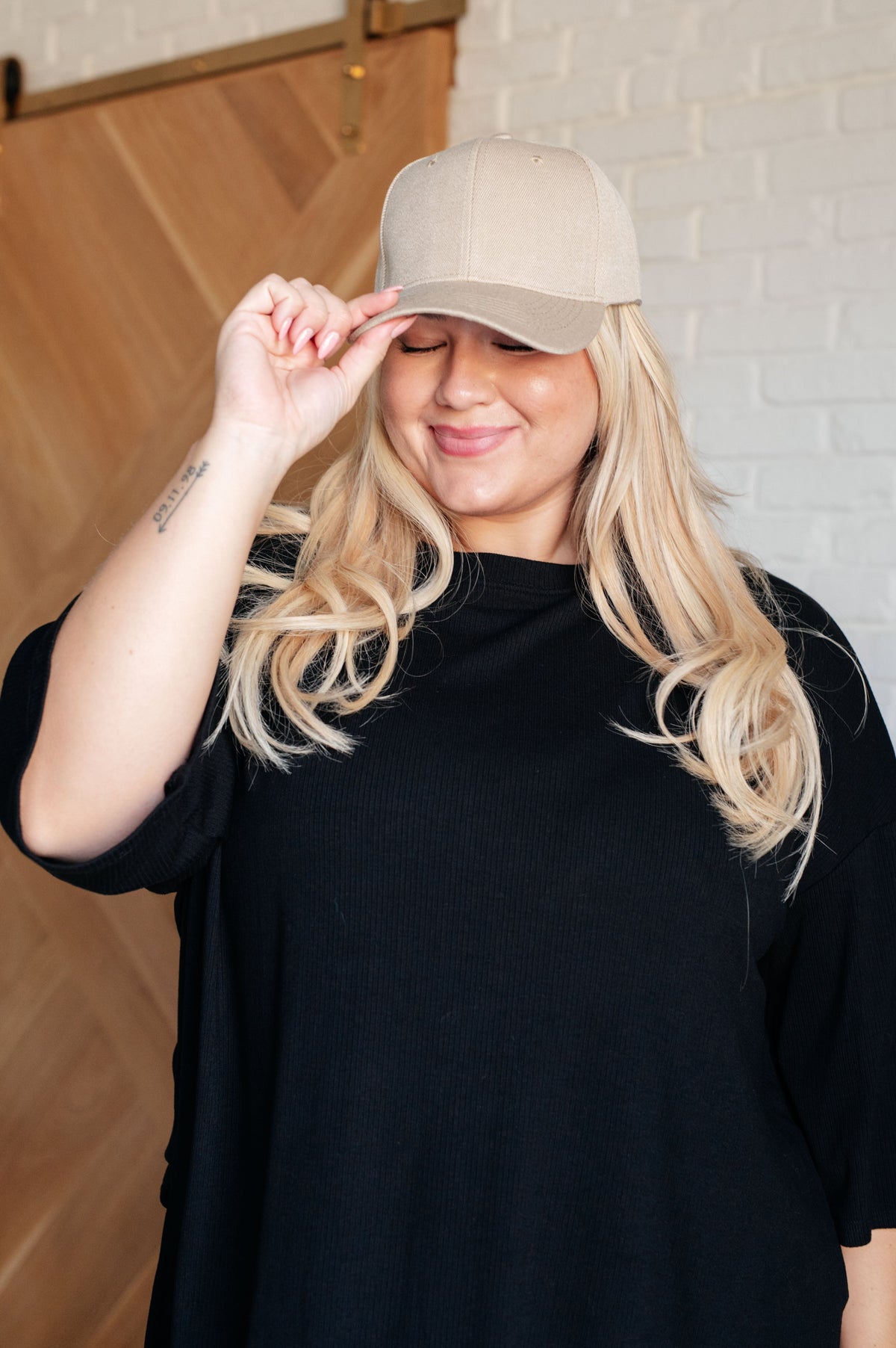 Person wearing a beige cap and black shirt against a neutral background