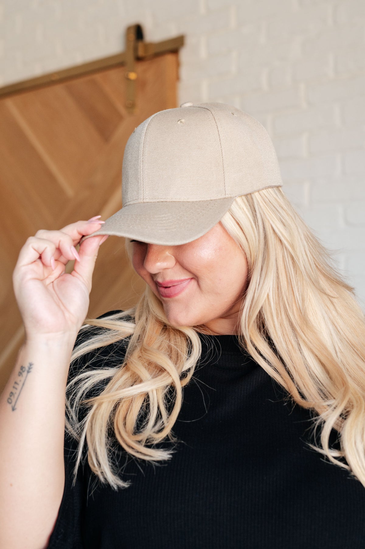 Woman holding a beige baseball cap against a neutral background