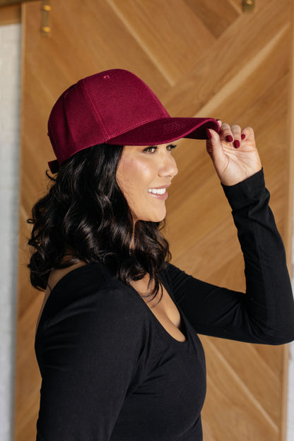 Woman wearing a maroon cap indoors against a wooden wall.